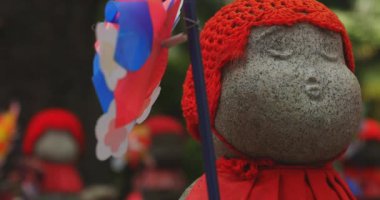 Heykel bekçisi kırmızı şapka takıyor. Tokyo Minato Bölgesi - 07.25.2019: Geleneksel tapınakta bulunan eski bir heykel.