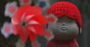 Tokyo gündüz el kamerasında kırmızı şapka takan heykel koruyucusu. Tokyo Minato Bölgesi - 07.25.2019: Geleneksel tapınakta bulunan eski bir heykel.