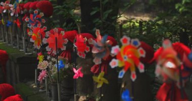 Odaklanırken kırmızı şapka takan heykel koruyucusu. Tokyo Minato Bölgesi - 07.25.2019: Geleneksel tapınakta bulunan eski bir heykel.