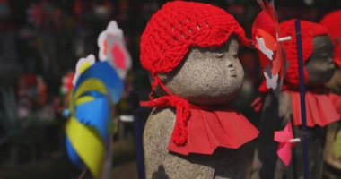 Tokyo gündüz el kamerasında kırmızı şapka takan heykel koruyucusu. Tokyo Minato Bölgesi - 07.25.2019: Geleneksel tapınakta bulunan eski bir heykel.