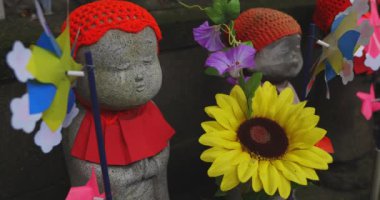 Heykel bekçisi kırmızı şapka takıyor. Tokyo Minato Bölgesi - 07.25.2019: Geleneksel tapınakta bulunan eski bir heykel.