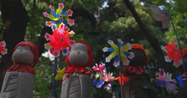 Tokyo gündüz el kamerasında kırmızı şapka takan heykel koruyucusu. Tokyo Minato Bölgesi - 07.25.2019: Geleneksel tapınakta bulunan eski bir heykel.