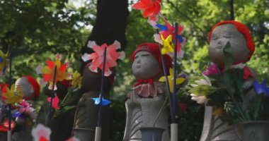 Tokyo gündüz el kamerasında kırmızı şapka takan heykel koruyucusu. Tokyo Minato Bölgesi - 07.25.2019: Geleneksel tapınakta bulunan eski bir heykel.