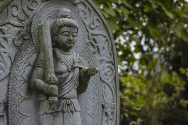 Japon tapınağında bir Budizm taşı heykeli. Yüksek kalite fotoğraf. Higashimurayama Bölgesi Tokyo Japonya 11.14.2024 Japon tapınağında bulunan bir dinsel taş heykel..