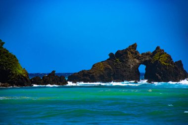 Tunnel rock cliff in the blue ocean . Amami oshima district Kagoshima Japan - 05.21.2019 This rock is called Turusu rock. clipart