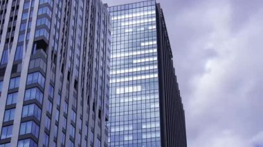 İş kasabasındaki ofis binasını yansıtan hareket eden bulutlar. Yüksek kalite 4K görüntü. Shinjuku Bölgesi Nishishinjuku Tokyo Japonya 06.27.2025 Tokyo 'nun merkezidir.. 