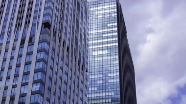 İş kasabasındaki ofis binasını yansıtan hareket eden bulutlar. Yüksek kalite 4K görüntü. Shinjuku Bölgesi Nishishinjuku Tokyo Japonya 06.27.2025 Tokyo 'nun merkezidir.. 