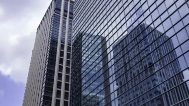 İş kasabasındaki ofis binasını yansıtan hareket eden bulutlar. Yüksek kalite 4K görüntü. Shinjuku Bölgesi Nishishinjuku Tokyo Japonya 06.27.2025 Tokyo 'nun merkezidir.. 