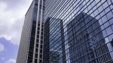 İş kasabasındaki ofis binasını yansıtan hareket eden bulutlar. Yüksek kalite 4K görüntü. Shinjuku Bölgesi Nishishinjuku Tokyo Japonya 06.27.2025 Tokyo 'nun merkezidir.. 