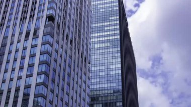 İş kasabasındaki ofis binasını yansıtan hareket eden bulutlar. Yüksek kalite 4K görüntü. Shinjuku Bölgesi Nishishinjuku Tokyo Japonya 06.27.2025 Tokyo 'nun merkezidir.. 