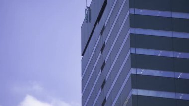 İş kasabasındaki ofis binasını yansıtan hareket eden bulutlar. Yüksek kalite 4K görüntü. Shinjuku Bölgesi Nishishinjuku Tokyo Japonya 06.27.2025 Tokyo 'nun merkezidir.. 