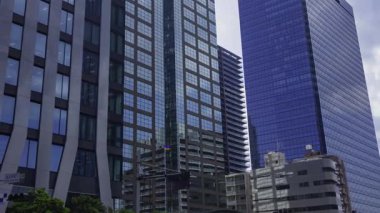 İş kasabasındaki ofis binasını yansıtan hareket eden bulutlar. Yüksek kalite 4K görüntü. Shinjuku Bölgesi Nishishinjuku Tokyo Japonya 06.27.2025 Tokyo 'nun merkezidir.. 