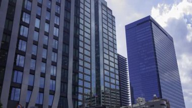 İş kasabasındaki ofis binasını yansıtan hareket eden bulutlar. Yüksek kalite 4K görüntü. Shinjuku Bölgesi Nishishinjuku Tokyo Japonya 06.27.2025 Tokyo 'nun merkezidir.. 