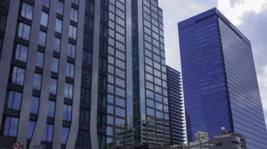 İş kasabasındaki ofis binasını yansıtan hareket eden bulutlar. Yüksek kalite 4K görüntü. Shinjuku Bölgesi Nishishinjuku Tokyo Japonya 06.27.2025 Tokyo 'nun merkezidir.. 