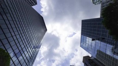 İş kasabasındaki ofis binasını yansıtan hareket eden bulutlar. Yüksek kalite 4K görüntü. Shinjuku Bölgesi Nishishinjuku Tokyo Japonya 06.27.2025 Tokyo 'nun merkezidir.. 