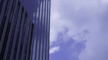 İş kasabasındaki ofis binasını yansıtan hareket eden bulutlar. Yüksek kalite 4K görüntü. Shinjuku Bölgesi Nishishinjuku Tokyo Japonya 06.27.2025 Tokyo 'nun merkezidir.. 