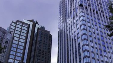 İş kasabasındaki ofis binasını yansıtan hareket eden bulutlar. Yüksek kalite 4K görüntü. Shinjuku Bölgesi Nishishinjuku Tokyo Japonya 06.27.2025 Tokyo 'nun merkezidir.. 