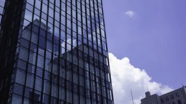 İş kasabasındaki ofis binasını yansıtan hareket eden bulutlar. Yüksek kalite 4K görüntü. Shinjuku Bölgesi Nishishinjuku Tokyo Japonya 06.27.2025 Tokyo 'nun merkezidir.. 