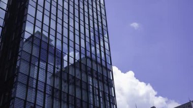 İş kasabasındaki ofis binasını yansıtan hareket eden bulutlar. Yüksek kalite 4K görüntü. Shinjuku Bölgesi Nishishinjuku Tokyo Japonya 06.27.2025 Tokyo 'nun merkezidir.. 