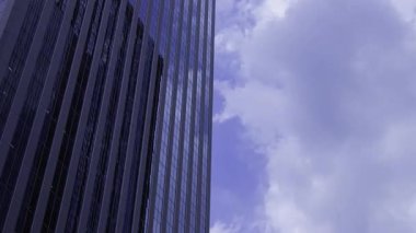 İş kasabasındaki ofis binasını yansıtan hareket eden bulutlar. Yüksek kalite 4K görüntü. Shinjuku Bölgesi Nishishinjuku Tokyo Japonya 06.27.2025 Tokyo 'nun merkezidir.. 