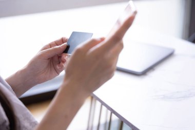 Kadının elleri oturma odasında kart ve akıllı telefondan alışveriş yapıyor. Yüksek kalite fotoğraf. Tokyo Japonya 06.19.2025