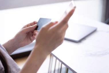 Kadının elleri oturma odasında kart ve akıllı telefondan alışveriş yapıyor. Yüksek kalite fotoğraf. Tokyo Japonya 06.19.2025