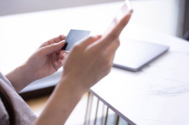 Kadının elleri oturma odasında kart ve akıllı telefondan alışveriş yapıyor. Yüksek kalite fotoğraf. Tokyo Japonya 06.19.2025