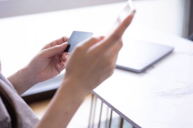 Kadının elleri oturma odasında kart ve akıllı telefondan alışveriş yapıyor. Yüksek kalite fotoğraf. Tokyo Japonya 06.19.2025