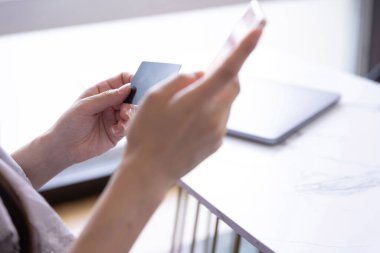 Kadının elleri oturma odasında kart ve akıllı telefondan alışveriş yapıyor. Yüksek kalite fotoğraf. Tokyo Japonya 06.19.2025