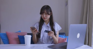 Oturma odasında elinde Card ve Smartphone olan bir Japon kadın. Yüksek kalite 4K görüntü. Tokyo Japonya 06.19.2025