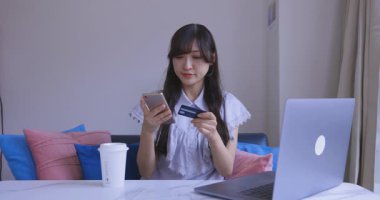 Oturma odasında elinde Card ve Smartphone olan bir Japon kadın. Yüksek kalite 4K görüntü. Tokyo Japonya 06.19.2025