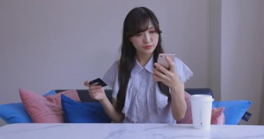 Oturma odasında elinde Card ve Smartphone olan bir Japon kadın. Yüksek kalite 4K görüntü. Tokyo Japonya 06.19.2025