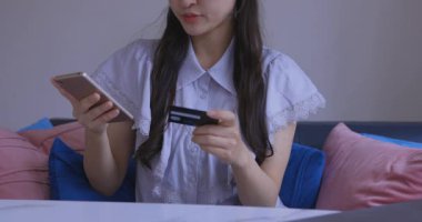 Oturma odasında elinde Card ve Smartphone olan bir Japon kadın. Yüksek kalite 4K görüntü. Tokyo Japonya 06.19.2025