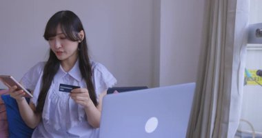 Oturma odasında elinde Card ve Smartphone olan bir Japon kadın. Yüksek kalite 4K görüntü. Tokyo Japonya 06.19.2025