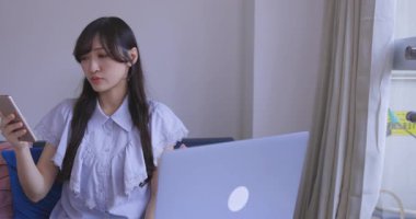 Oturma odasında elinde Card ve Smartphone olan bir Japon kadın. Yüksek kalite 4K görüntü. Tokyo Japonya 06.19.2025