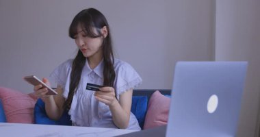 Oturma odasında elinde Card ve Smartphone olan bir Japon kadın. Yüksek kalite 4K görüntü. Tokyo Japonya 06.19.2025