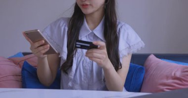 Oturma odasında elinde Card ve Smartphone olan bir Japon kadın. Yüksek kalite 4K görüntü. Tokyo Japonya 06.19.2025