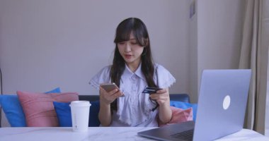 Oturma odasında elinde Card ve Smartphone olan bir Japon kadın. Yüksek kalite 4K görüntü. Tokyo Japonya 06.19.2025