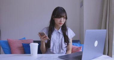 Oturma odasında elinde Card ve Smartphone olan bir Japon kadın. Yüksek kalite 4K görüntü. Tokyo Japonya 06.19.2025