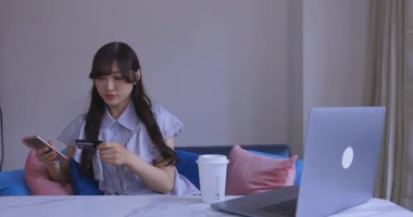 Oturma odasında elinde Card ve Smartphone olan bir Japon kadın. Yüksek kalite 4K görüntü. Tokyo Japonya 06.19.2025