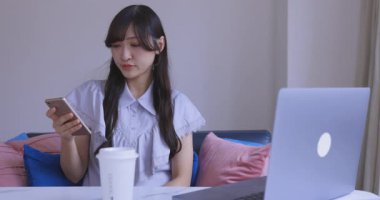 Japon bir kadın oturma odasında akıllı telefondan alışveriş yapıyor. Yüksek kalite 4K görüntü. Tokyo Japonya 06.12.2025