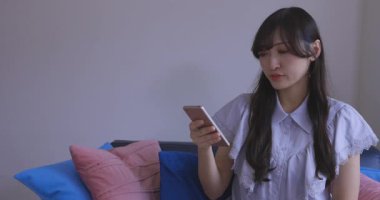 Japon bir kadın oturma odasında akıllı telefondan alışveriş yapıyor. Yüksek kalite 4K görüntü. Tokyo Japonya 06.12.2025