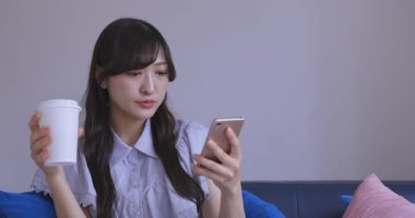 Japon bir kadın oturma odasında akıllı telefondan alışveriş yapıyor. Yüksek kalite 4K görüntü. Tokyo Japonya 06.12.2025