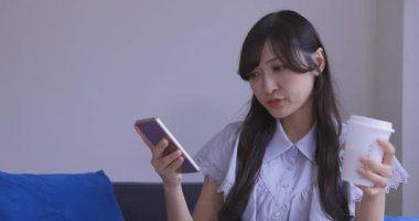 Japon bir kadın oturma odasında akıllı telefondan alışveriş yapıyor. Yüksek kalite 4K görüntü. Tokyo Japonya 06.12.2025