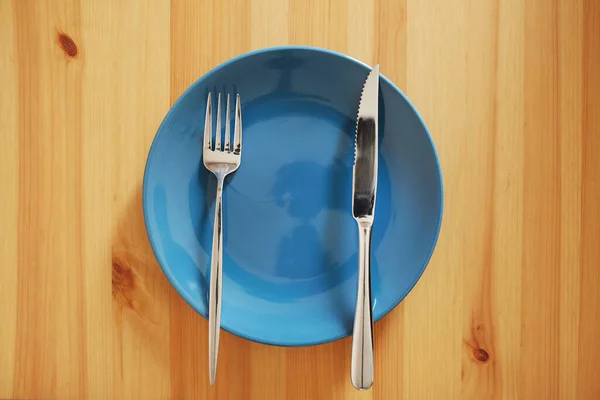 食事は終わりました という合図 テーブルエチケットの例として 木製のテーブルの上にフォークとナイフで空ときれいな青のプレート — ストック写真