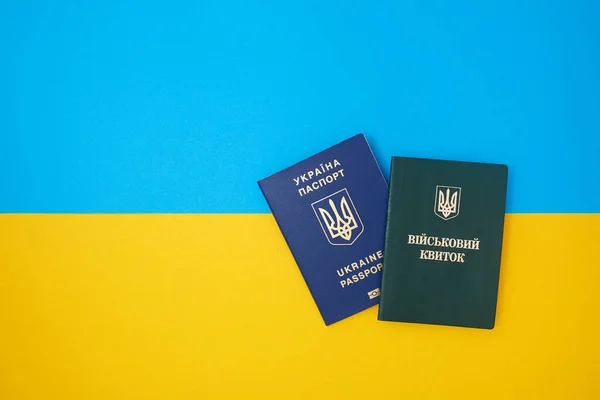 Ukrainian green military ID ticket on the Ukrainian national flag in the top view. Translation: \
