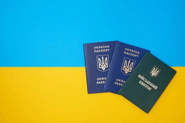 Ukrainian green military ID ticket on the Ukrainian national flag in the top view. Translation: \