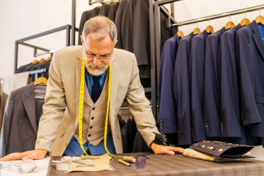 şık ve zengin takım elbiseli yaşlı yakışıklı adam atölyenin sahibi işiyle meşgul..