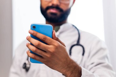 Hastanede cep telefonuyla başvuru yapan neşeli Hintli doktor..