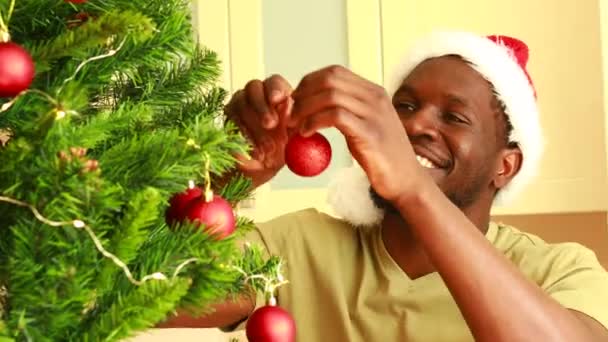 Afro Amerikaneren Nisselue Dekorerer Juletreet Med Rød Ball Hjemme – stockvideo